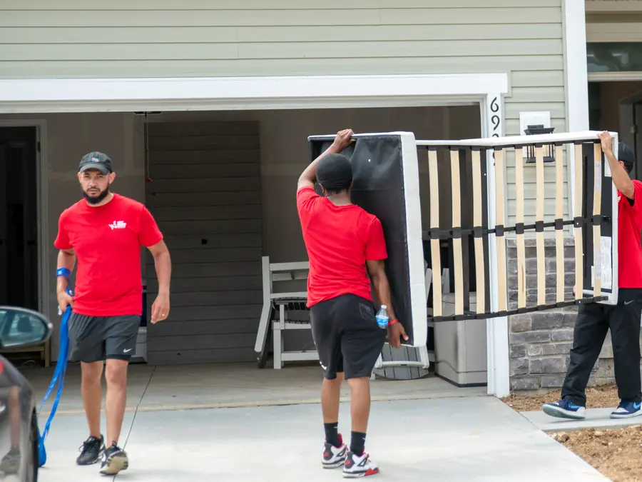 Dolly Donkeys movers carrying a bed frame into a new home
