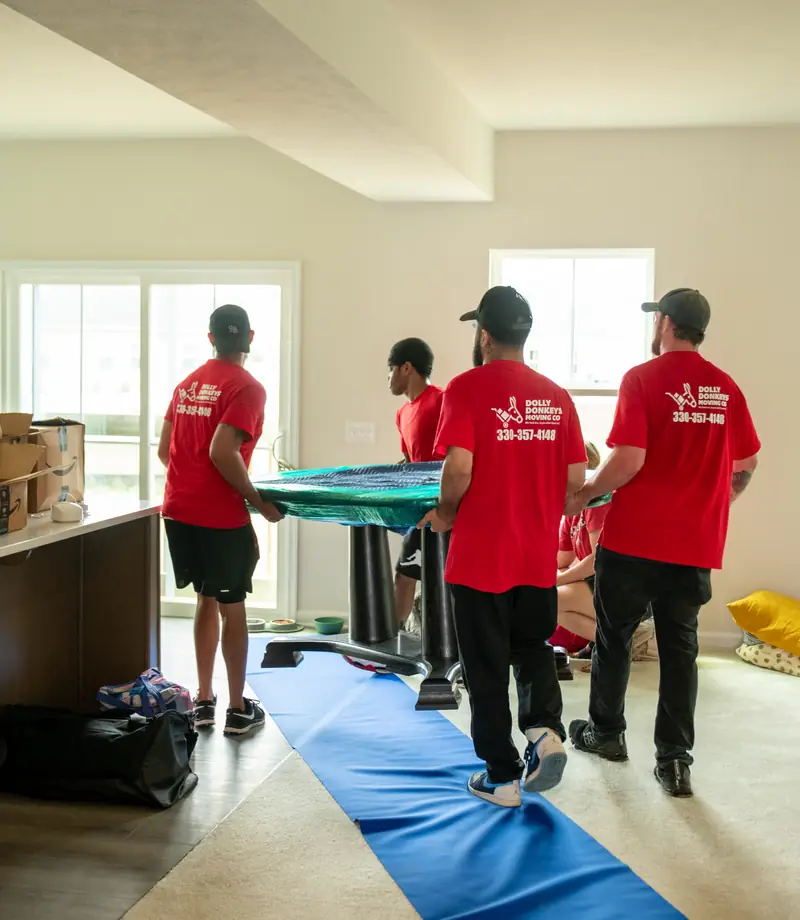 The crew carrying a wrapped table into a customer's new home