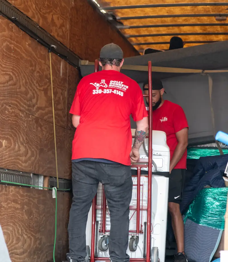 Movers strapping an appliance to the dolly inside the truck