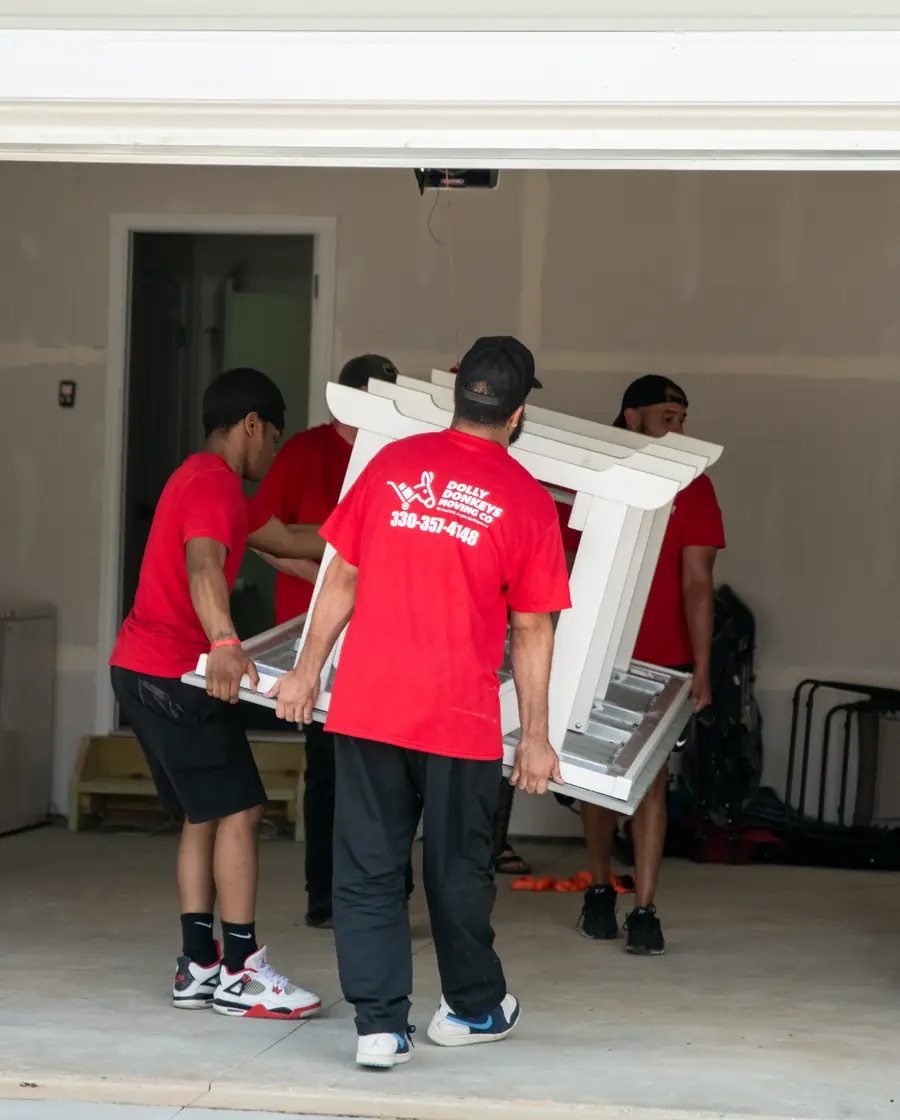 The Dolly Donkeys crew carrying furniture through the garage